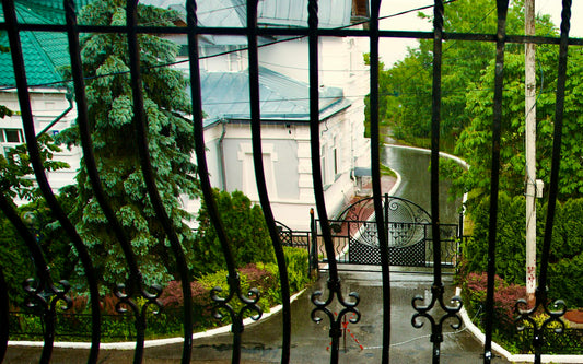 Wet driveway seen through a black metal gate